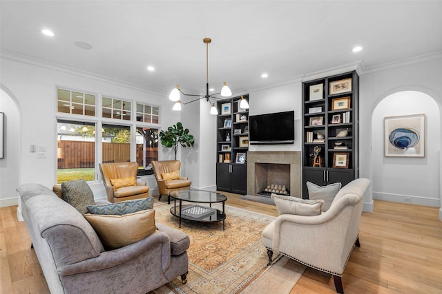 living room featuring a chandelier, ornamental molding, and light wood-type flooring