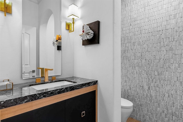 bathroom with vanity, toilet, and tile walls