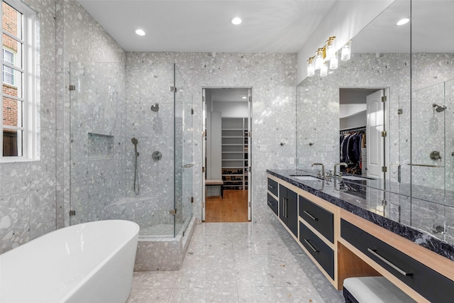 bathroom featuring shower with separate bathtub, vanity, and tile walls