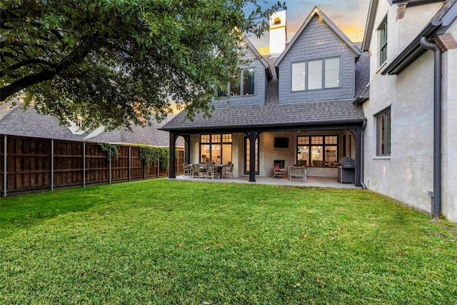 back house at dusk with a yard and a patio