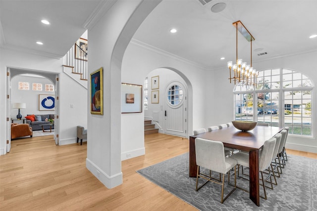 dining space with light wood-type flooring, ornamental molding, and a chandelier