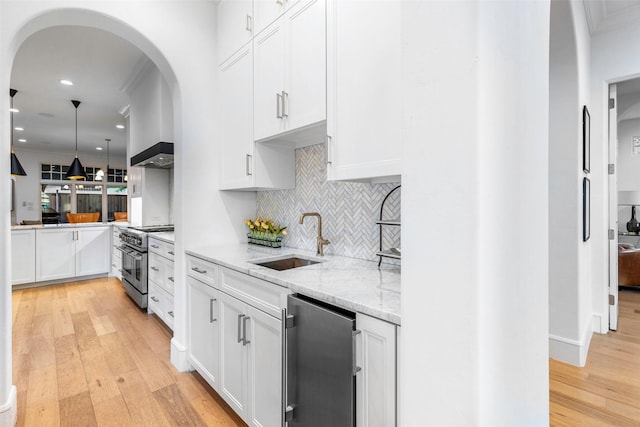 kitchen featuring sink, hanging light fixtures, light hardwood / wood-style floors, white cabinets, and appliances with stainless steel finishes