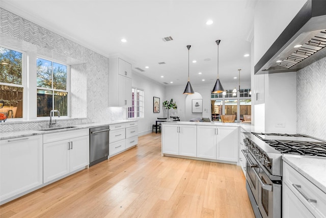 kitchen featuring white cabinetry, sink, stainless steel appliances, and wall chimney range hood