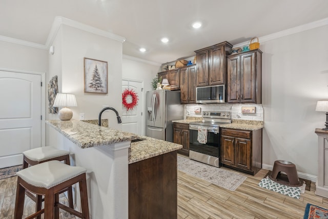 kitchen with a breakfast bar, light hardwood / wood-style floors, light stone counters, and stainless steel appliances