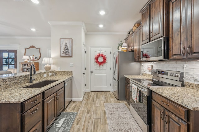 kitchen with crown molding, sink, light stone countertops, dark brown cabinetry, and stainless steel appliances