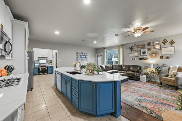 kitchen featuring a sink, white cabinets, open floor plan, light countertops, and blue cabinetry