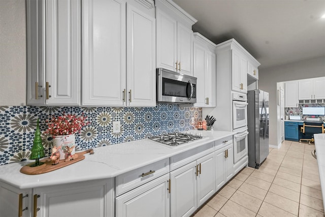 kitchen featuring light tile patterned floors, white cabinetry, appliances with stainless steel finishes, and decorative backsplash