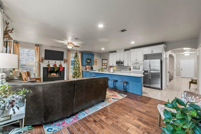 kitchen featuring blue cabinetry, stainless steel appliances, light countertops, open floor plan, and white cabinets