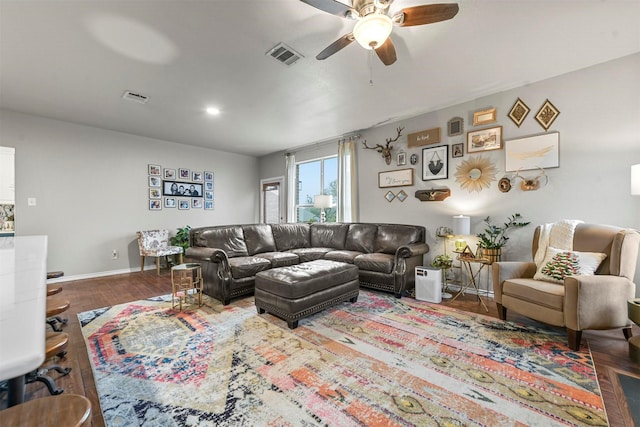 living area with a ceiling fan, wood finished floors, visible vents, and baseboards