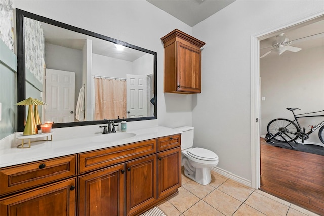 bathroom featuring ceiling fan, tile patterned flooring, toilet, vanity, and baseboards