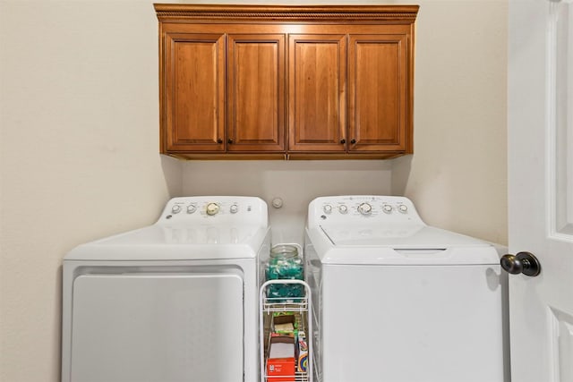 clothes washing area featuring washing machine and dryer and cabinet space