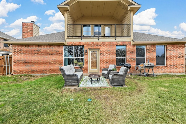 rear view of property featuring a balcony, a fire pit, brick siding, a shingled roof, and a patio area