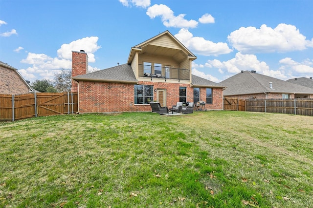 back of house featuring a fenced backyard, brick siding, a balcony, and an outdoor hangout area