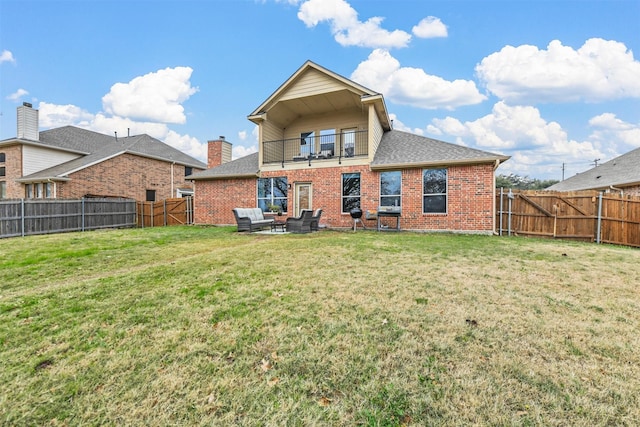 back of property with a fenced backyard, brick siding, a balcony, and an outdoor hangout area