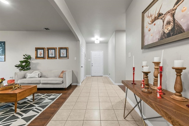 entrance foyer with arched walkways, light tile patterned floors, visible vents, and baseboards