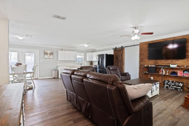 living room with ornamental molding, a barn door, and hardwood / wood-style floors