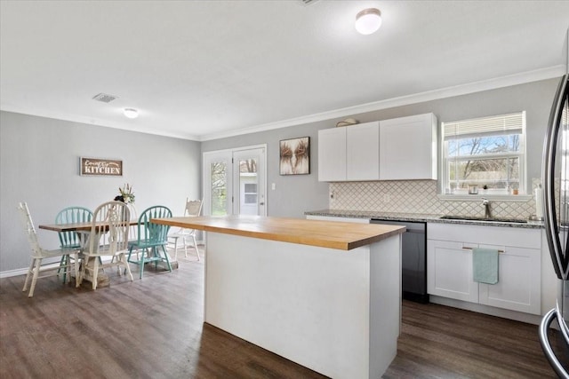 kitchen with butcher block counters, sink, dishwasher, a kitchen island, and white cabinets