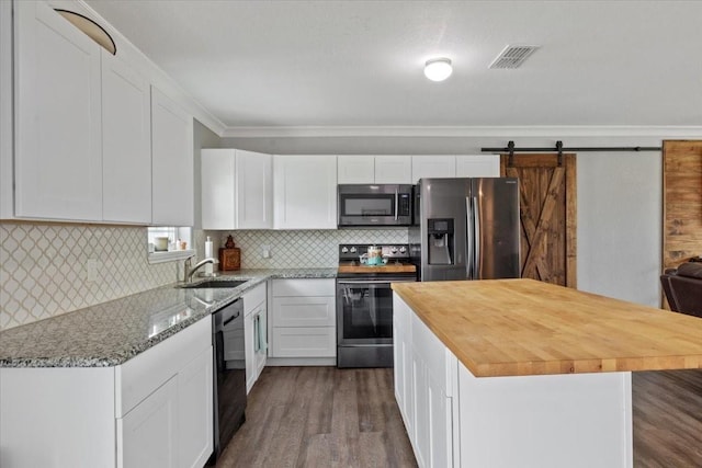 kitchen with a barn door, a center island, white cabinets, and appliances with stainless steel finishes