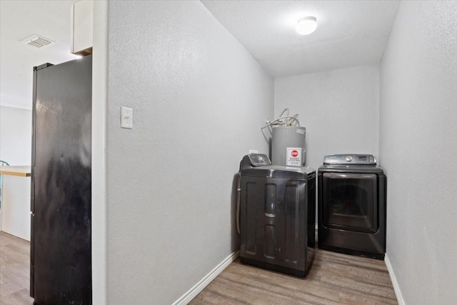 washroom with light hardwood / wood-style flooring, washing machine and dryer, and water heater