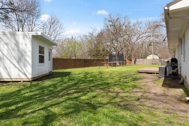 view of yard with central AC unit, a deck, a trampoline, and a storage shed