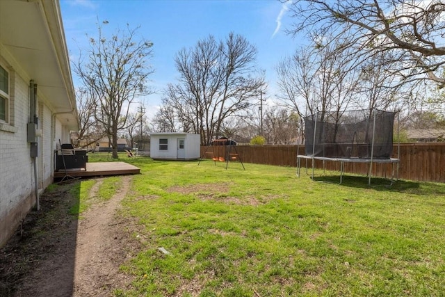 view of yard with a trampoline, a deck, a playground, and a storage unit