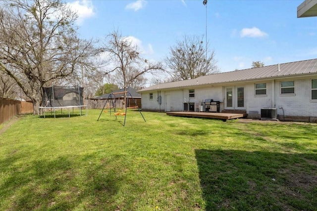 view of yard featuring a wooden deck, a playground, a trampoline, and cooling unit