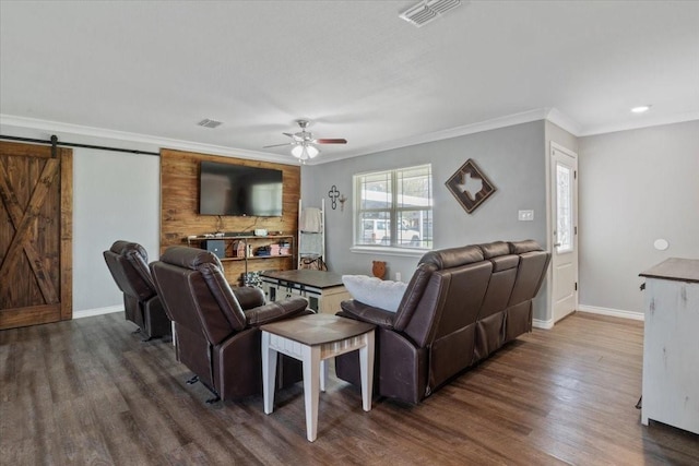 living room with dark hardwood / wood-style flooring, ornamental molding, a barn door, and ceiling fan