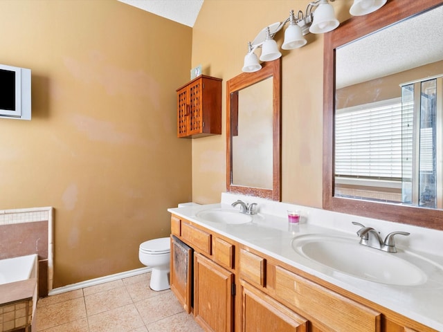 bathroom featuring tile patterned flooring, a tub to relax in, a textured ceiling, toilet, and vanity