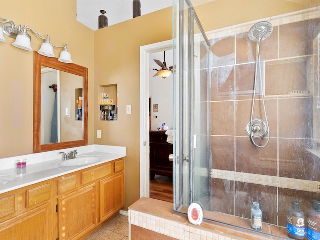 bathroom with tile patterned flooring, a tile shower, and vanity