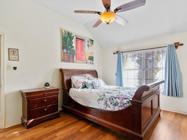 bedroom with hardwood / wood-style flooring, ceiling fan, a textured ceiling, and vaulted ceiling