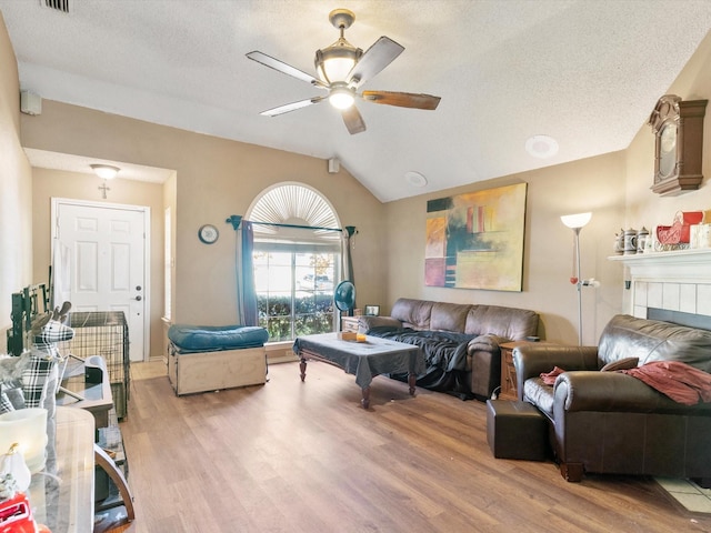 living room with ceiling fan, light hardwood / wood-style floors, lofted ceiling, and a fireplace