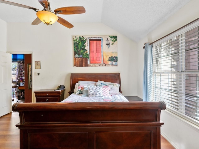 bedroom featuring a textured ceiling, ceiling fan, light hardwood / wood-style flooring, and lofted ceiling