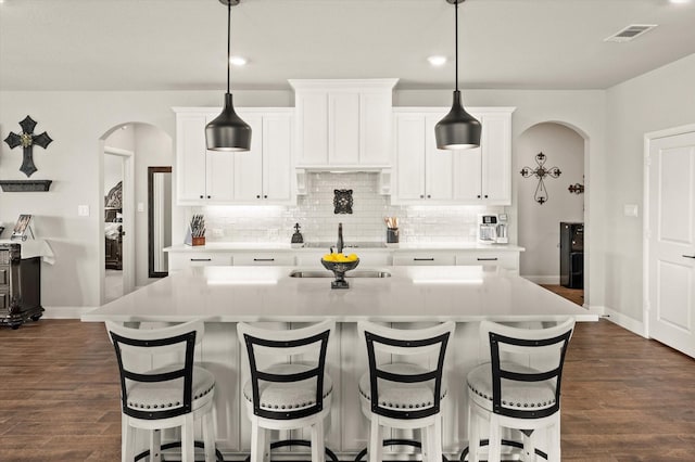 kitchen with a center island with sink, white cabinetry, and dark wood-type flooring