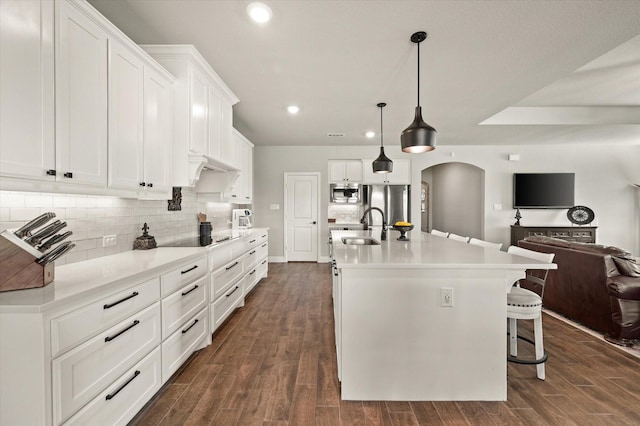 kitchen with dark hardwood / wood-style flooring, sink, white cabinets, hanging light fixtures, and an island with sink