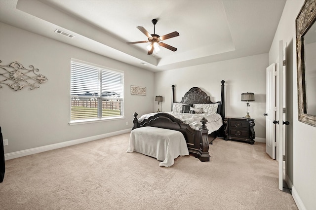 carpeted bedroom with ceiling fan and a raised ceiling