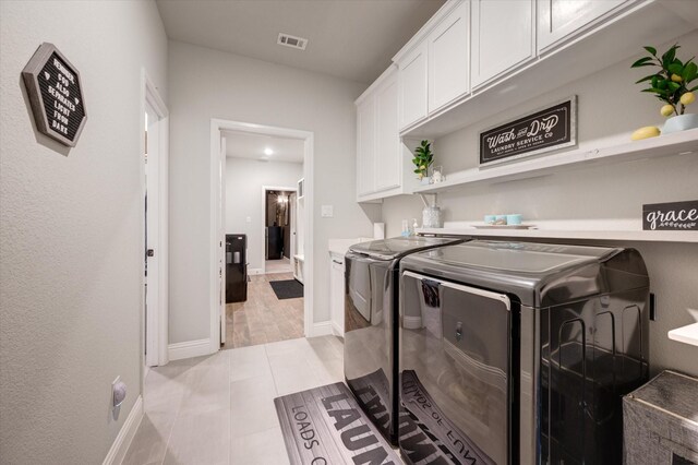 washroom featuring separate washer and dryer, light tile patterned floors, and cabinets