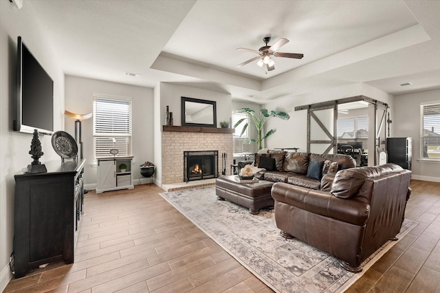 living room featuring hardwood / wood-style flooring, a tray ceiling, and a healthy amount of sunlight