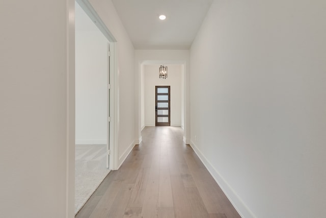 corridor featuring a notable chandelier and light hardwood / wood-style floors