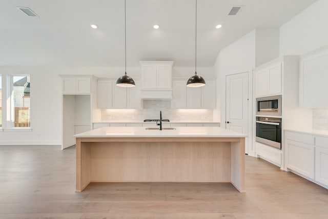 912 Shady Oaks Dr, Rockwall, TX 75087 - kitchen featuring stainless steel appliances, backsplash, a center island with sink, light countertops, and white cabinetry