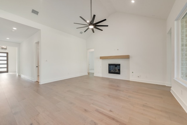 unfurnished living room with light hardwood / wood-style flooring, high vaulted ceiling, and ceiling fan with notable chandelier