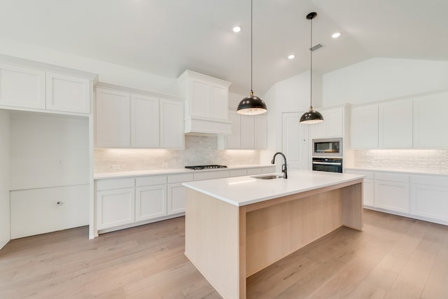 kitchen featuring sink, white cabinetry, lofted ceiling, an island with sink, and built in microwave