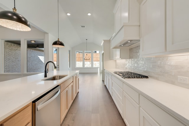 kitchen featuring sink, white cabinetry, vaulted ceiling, light brown cabinetry, and appliances with stainless steel finishes