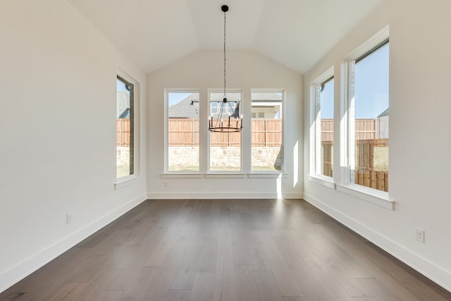 unfurnished dining area featuring lofted ceiling, dark wood-type flooring, and a chandelier