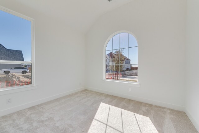 carpeted empty room with lofted ceiling