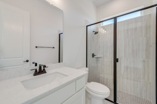 bathroom with toilet, a shower with door, and vanity