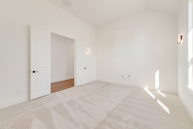 empty room with lofted ceiling and light carpet