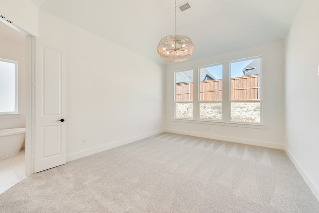 carpeted empty room with an inviting chandelier