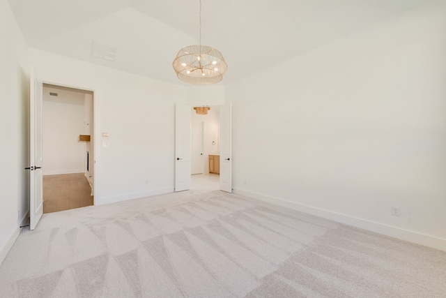 spare room with lofted ceiling, a chandelier, and light colored carpet