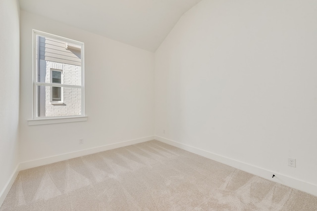 carpeted empty room featuring lofted ceiling