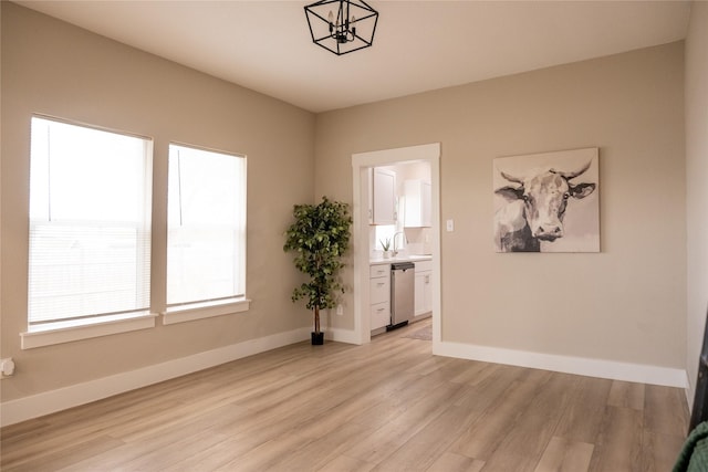 unfurnished room featuring a notable chandelier, sink, and light hardwood / wood-style flooring